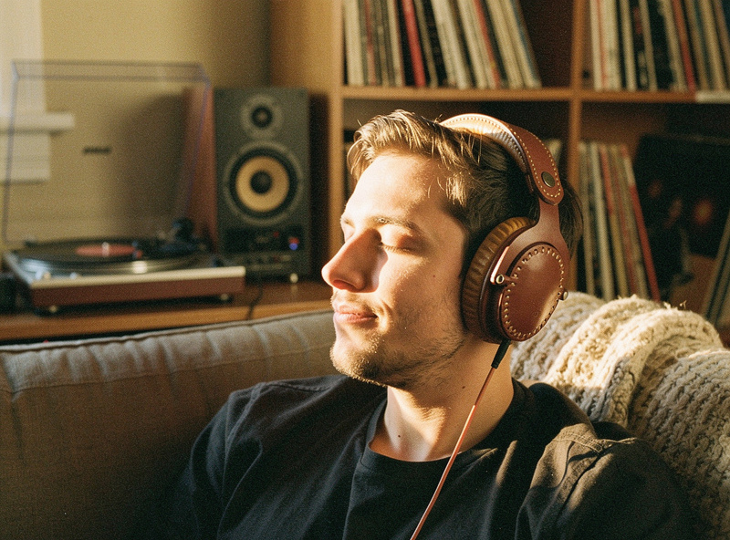 Audiophile wearing handmade brown leather over-ear headphones in a warm living room