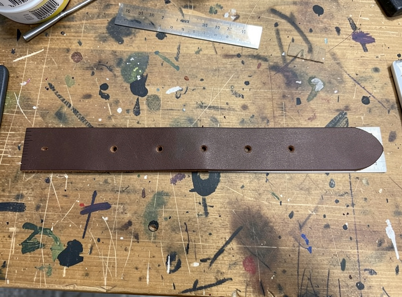 Five evenly spaced adjustment holes punched on the centerline of a leather dog collar strap