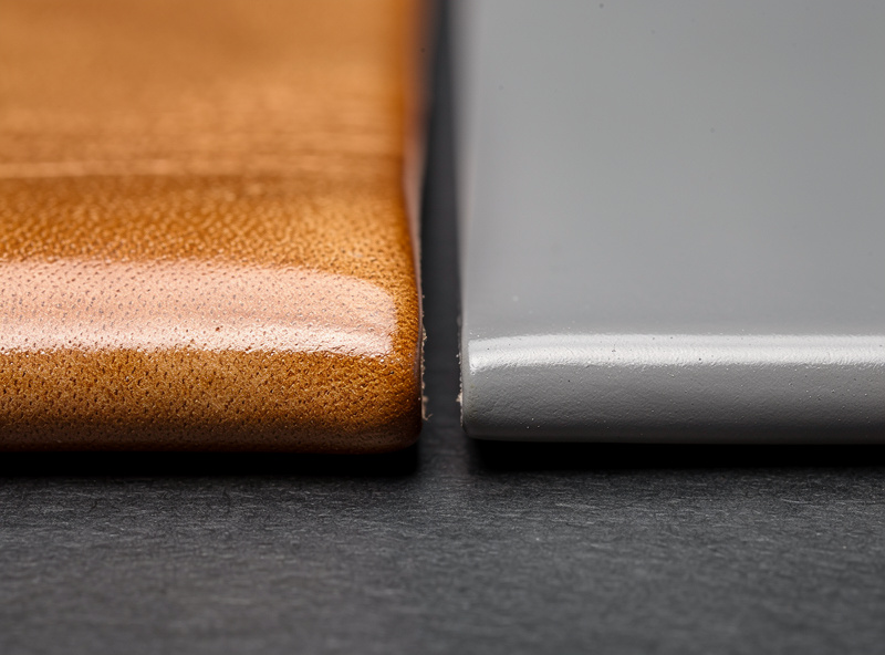 Close-up of a burnished veg-tan edge next to a painted chrome-tan edge on finished leather goods