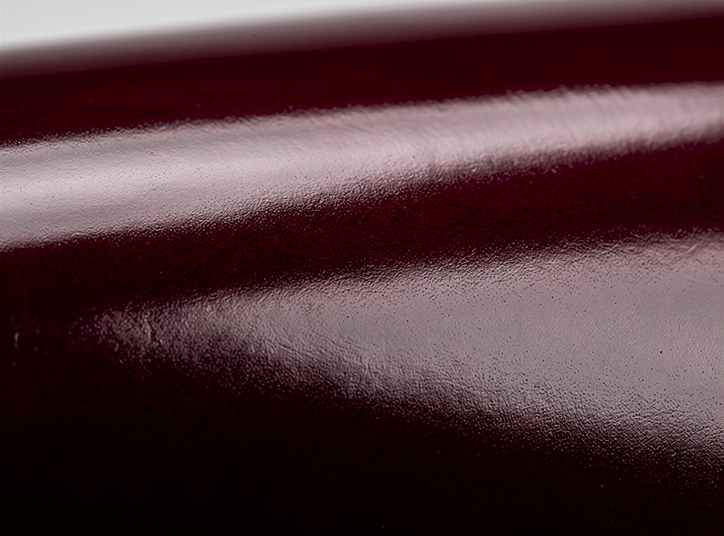 A piece of polished burgundy shell cordovan leather showing its deep glassy non-grain surface