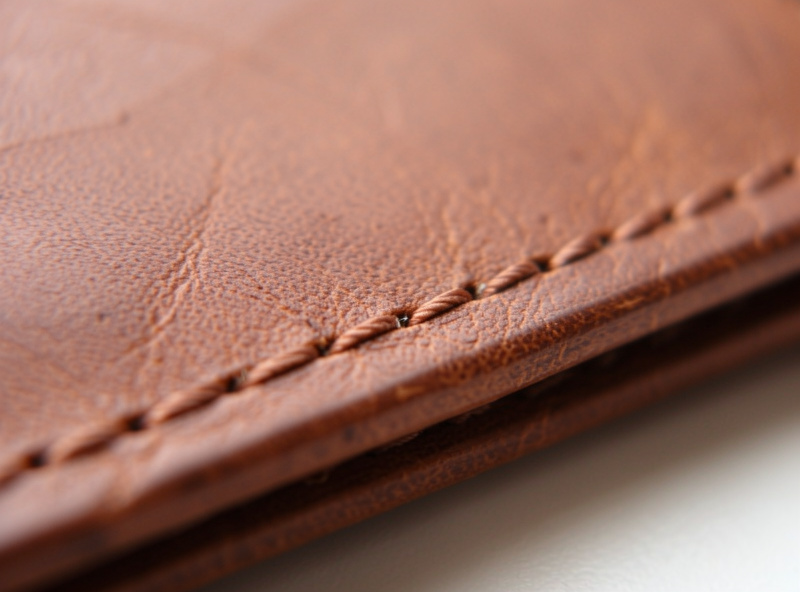A fine creased line running parallel just inside the edge of a finished veg-tan leather wallet