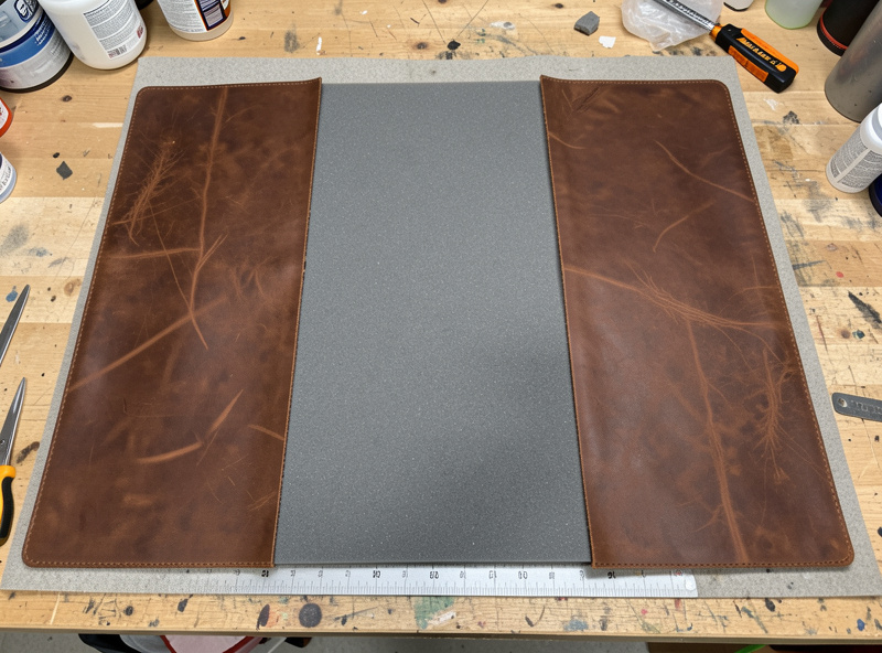 Heavy veg-tan leather panels and closed-cell foam padding laid out for a laptop bag build