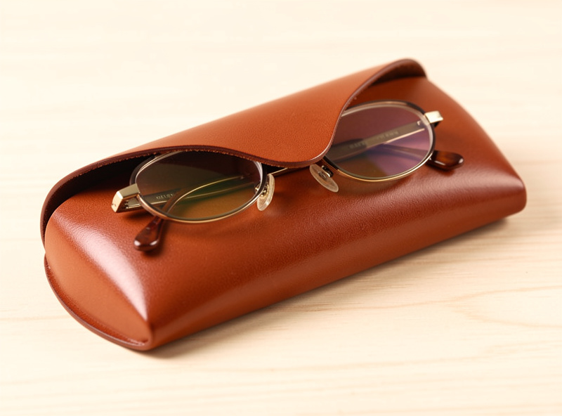 A finished custom-molded leather case holding eyeglasses snugly, slicked edges, on a workbench