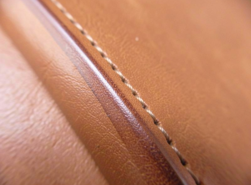 A finished beveled and burnished veg-tan leather edge running alongside a machine topstitch line