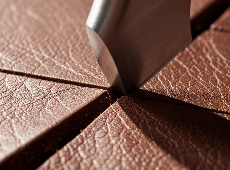 Close-up of a beveler walking along a swivel knife cut on tooled leather