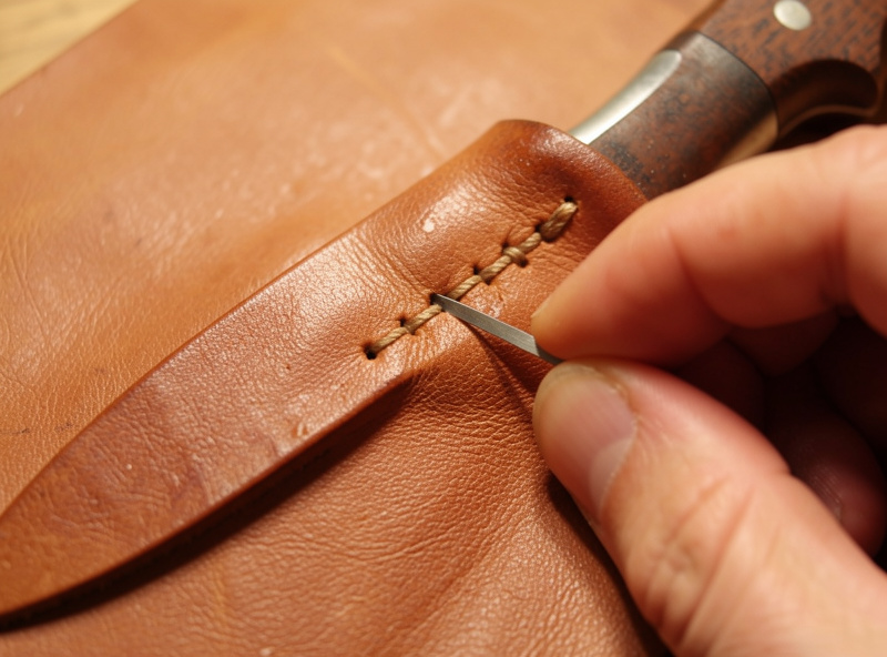 Vegetable-tanned leather sheath being pressed around a knife on a workshop bench
