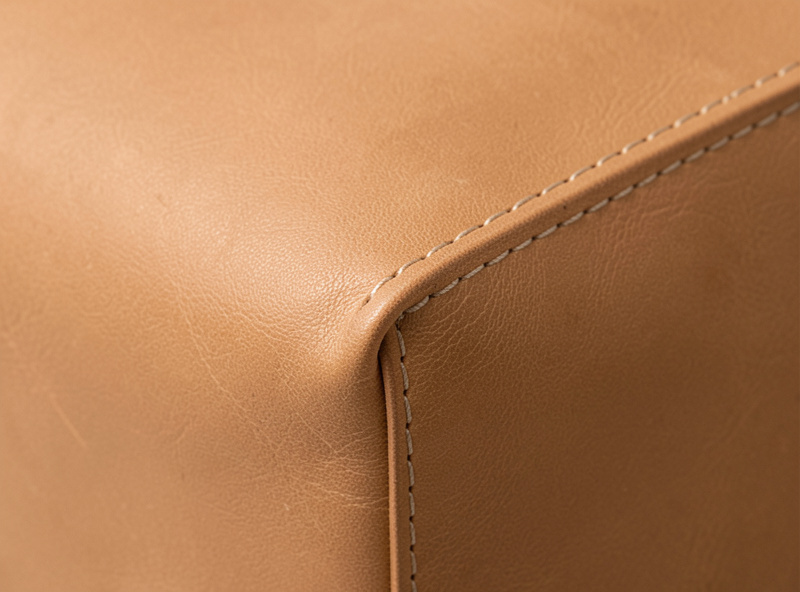 Finished machine-stitched leather bag panel showing an even topstitch line along a turned edge