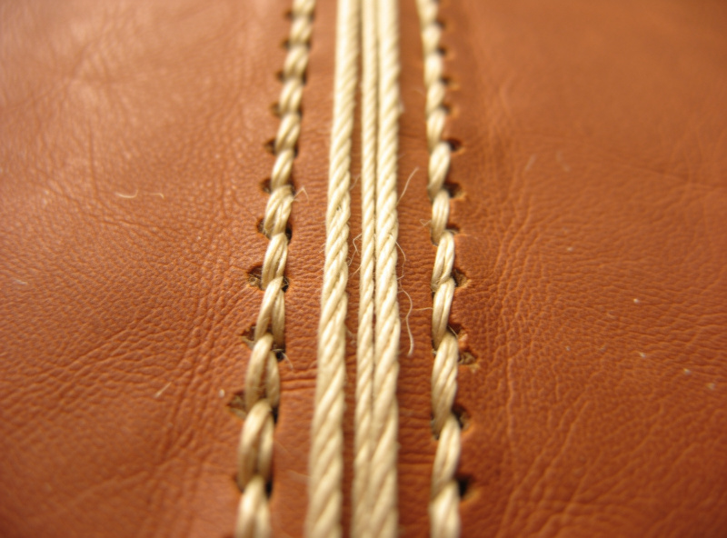 Close-up of a long-stitch pattern sewn through the spine of a leather journal cover with waxed linen thread