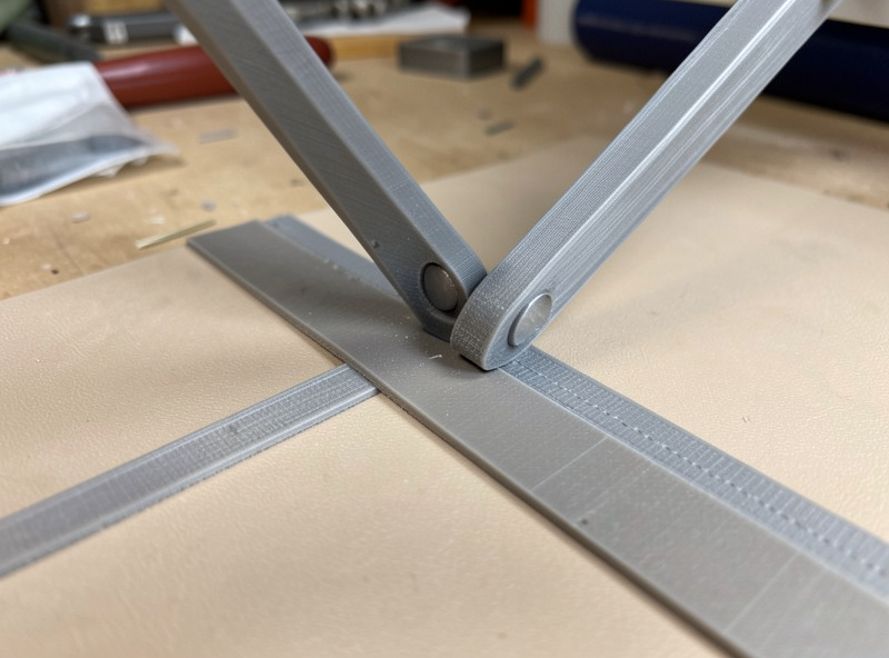 A 3D-printed folding jig guiding a skived leather edge into a flat turned fold ready for machine topstitching