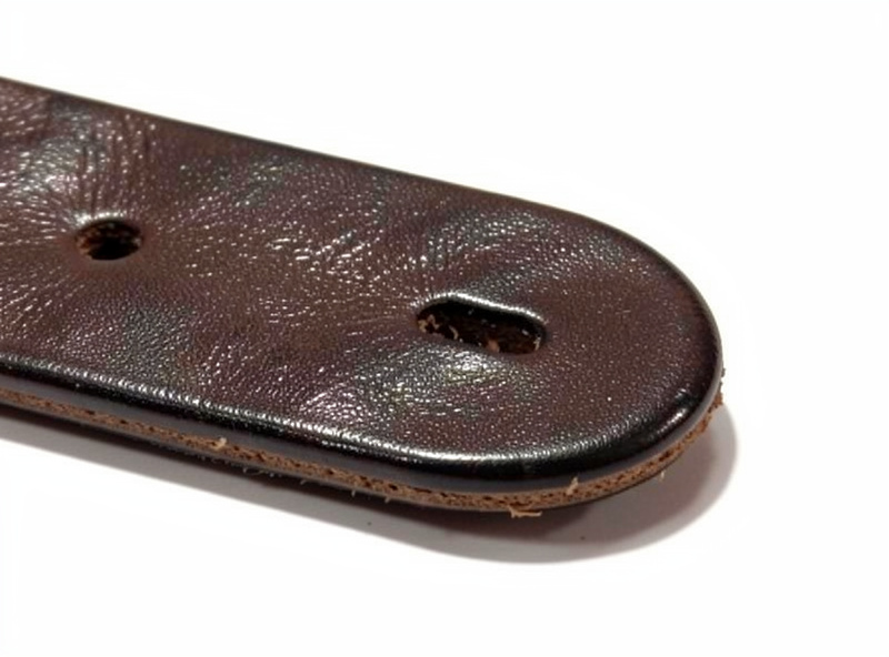 Close-up of a slotted keyhole end tab on a leather guitar strap cut for a strap button