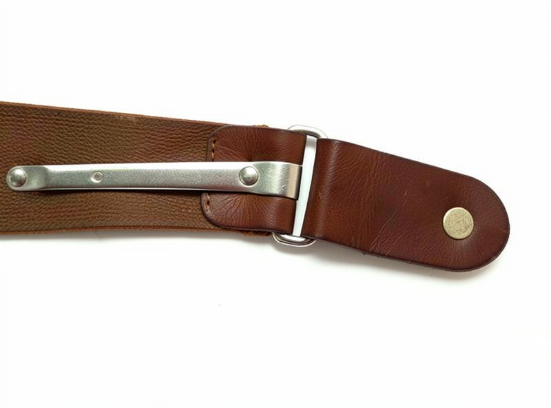 Close-up of a sliding leather suspender adjuster with a metal slide bar and a button tab end