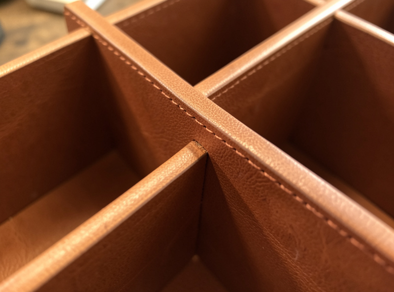Close-up of a stitched internal leather divider separating two compartments in a desk organizer