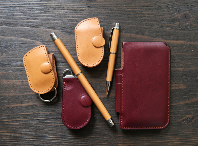 Flat lay of finished handmade leather EDC goods: key fob, key case, pen slip and phone sleeve