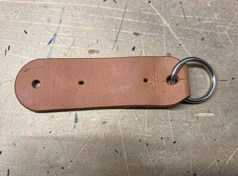 Flat cut strip of thick veg-tan leather for a key fob with rounded ends and marked holes