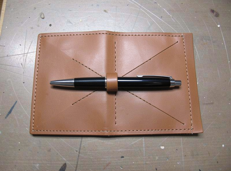 Flat folded leather panel for a pen slip with a pen laid on top for sizing