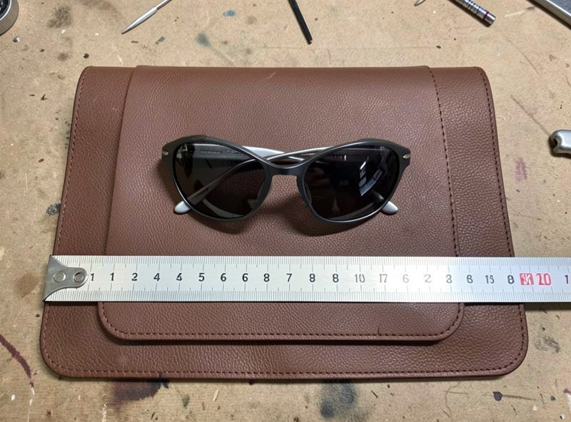 Folded sunglasses laid on flat leather being measured for a case pattern