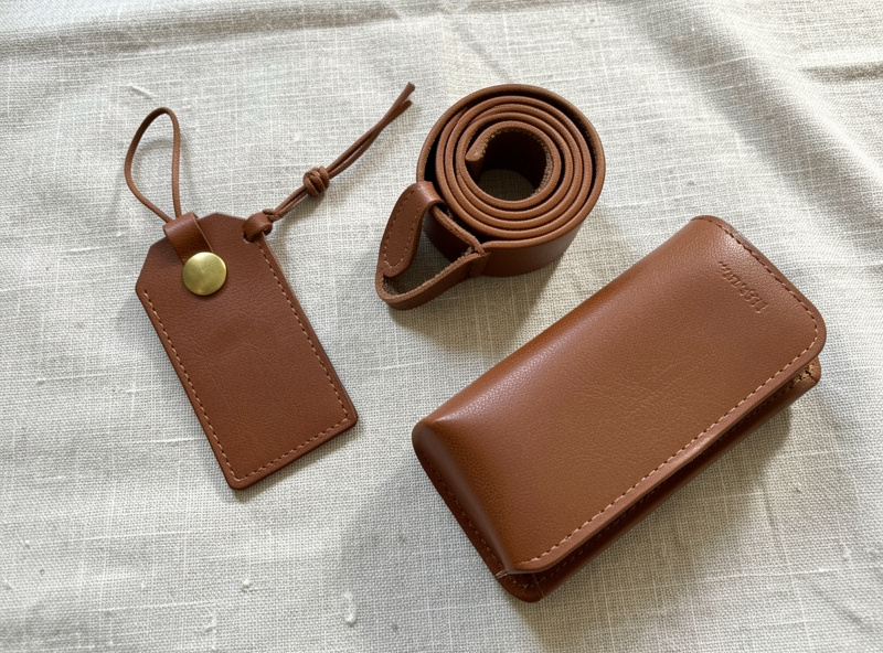Flat-lay of leather travel accessories on a linen surface